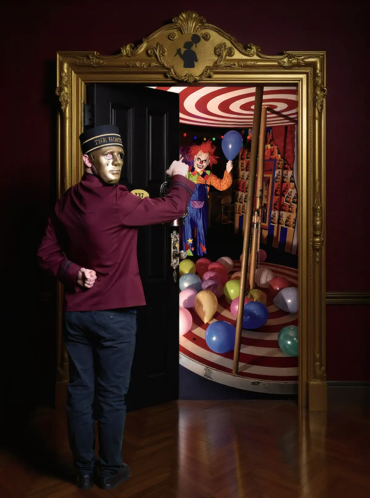 Un majordome masqué ouvre une porte dorée sur un décor de cirque effrayant, avec un clown tenant un ballon bleu et des ballons multicolores éparpillés au sol