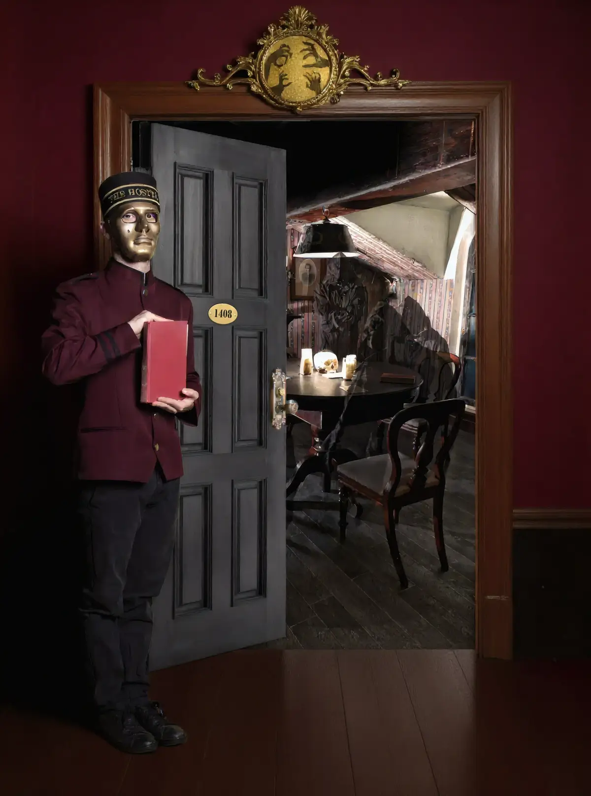 Un majordome au visage doré et mystérieux, vêtu d’un uniforme victorien, tient un livre rouge à l’entrée de la chambre, révélant une scène d’horreur avec des personnages effrayants attablés dans une ambiance sombre et victorienne.