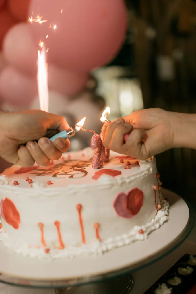Mains allumant les bougies d’un gâteau d’anniversaire décoré