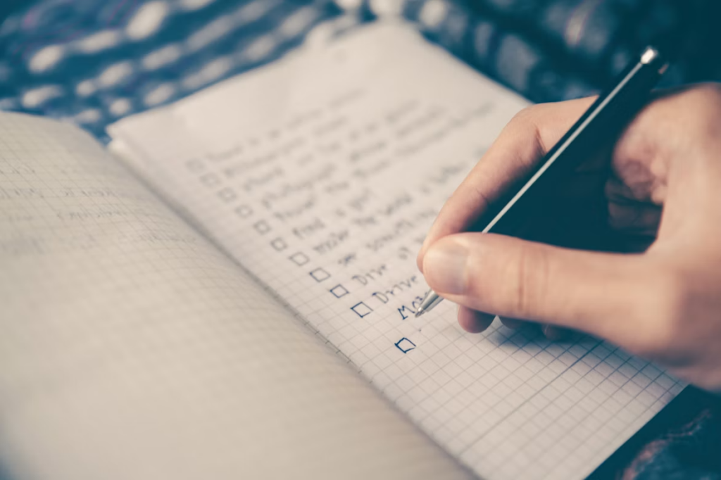 Main écrivant une liste au stylo dans un carnet